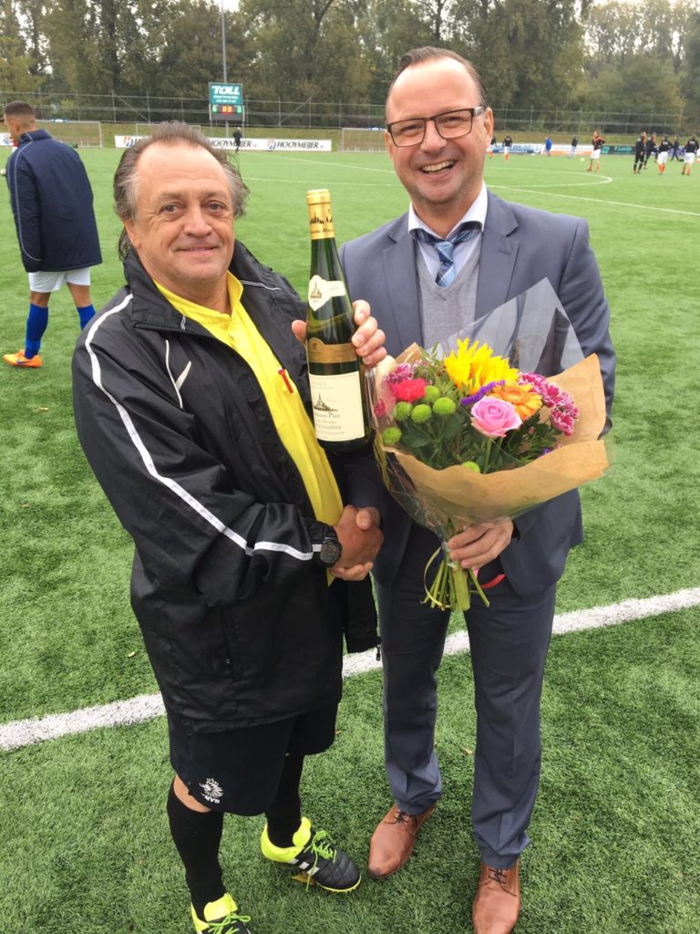Rikus is trots op de fles wijn en bloemen die hij krijgt vanwege 3000 wedstrijden
